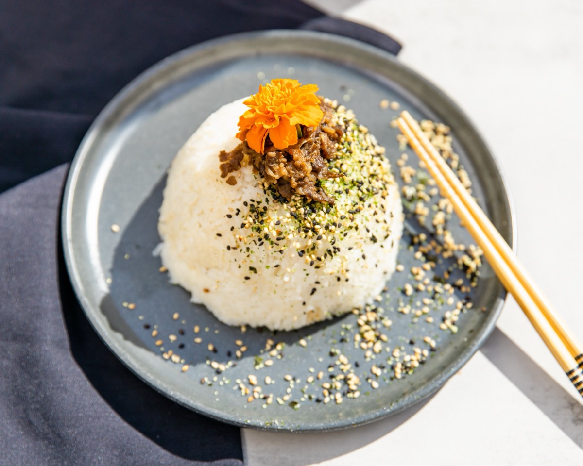 OniGuru rice bowl — hand-shaped mound of rice with KBBQ-style topping, sesame and furikake
